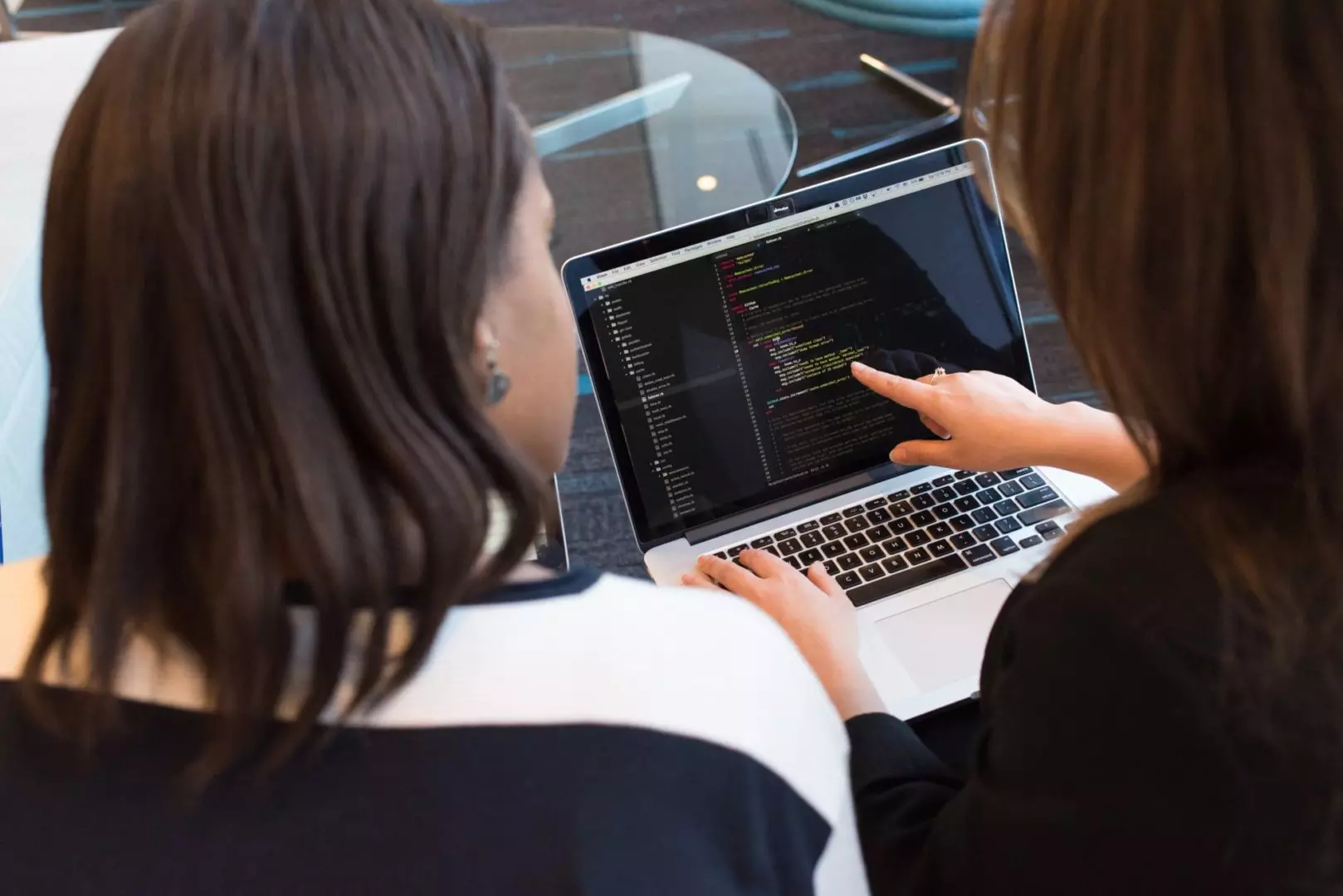 Two people lookingpointing at code on laptop